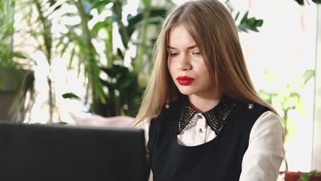 mujer joven trabajando en una computadora portátil en un café