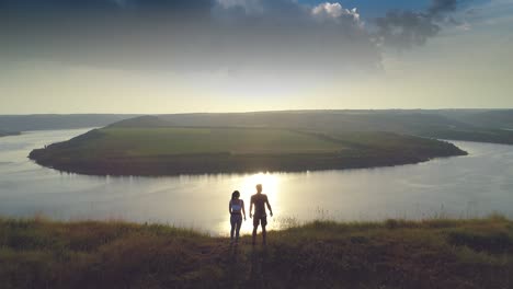 the man and woman standing on the mountain top against the river. slow motion