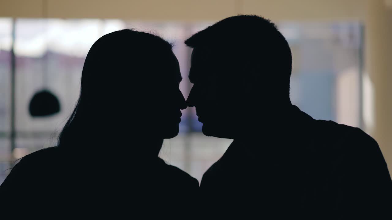 Enamored ?ouple are flirting in the restaurant on the background of the window. Silhouette of man and woman. Date in the cafe.