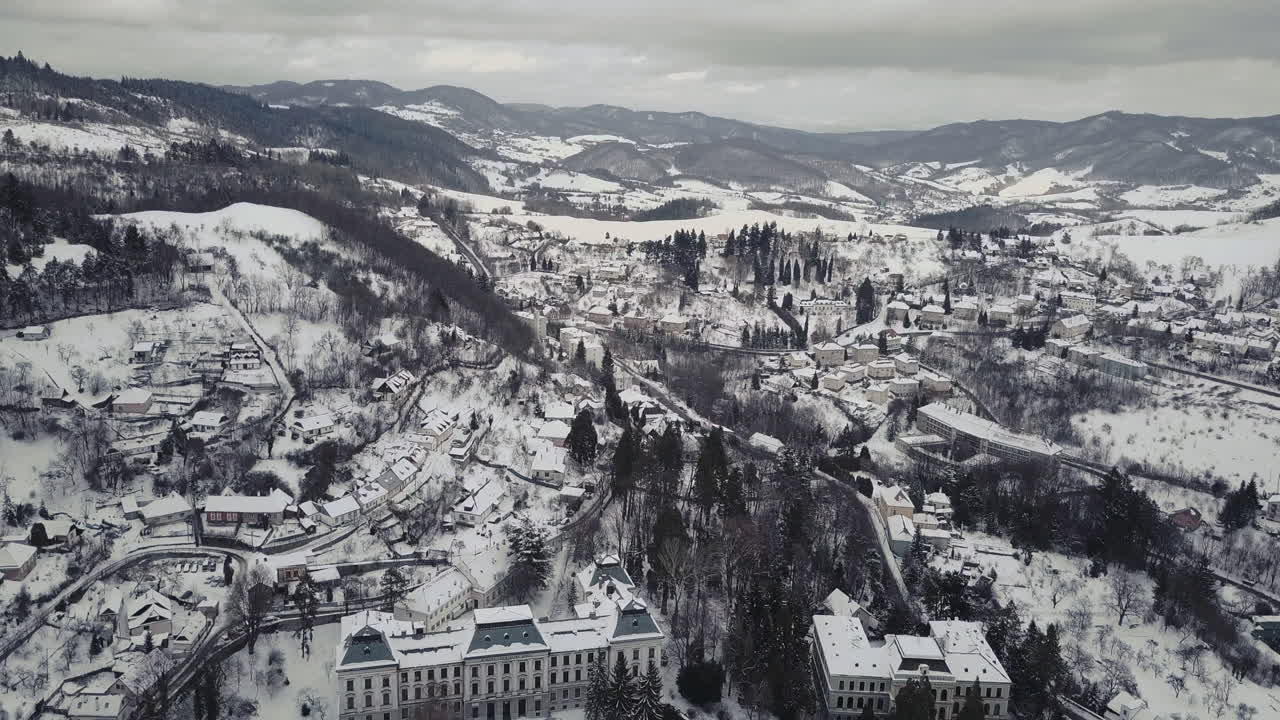 fotografía aérea amplia de una ciudad minera banska stiavnica en invierno cubierta de nieve, montañas en el fondo, nublada