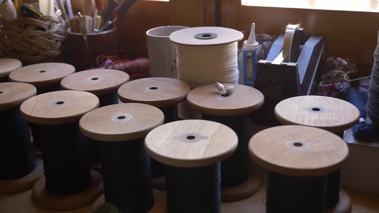 Large and small wooden spools of thread in a weaving workshop. It shows the supplies ready to be used