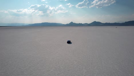 drone high angle shot over black car passing over bonneville salt flats in tooele county in northwestern, utah, usa on a sunny day