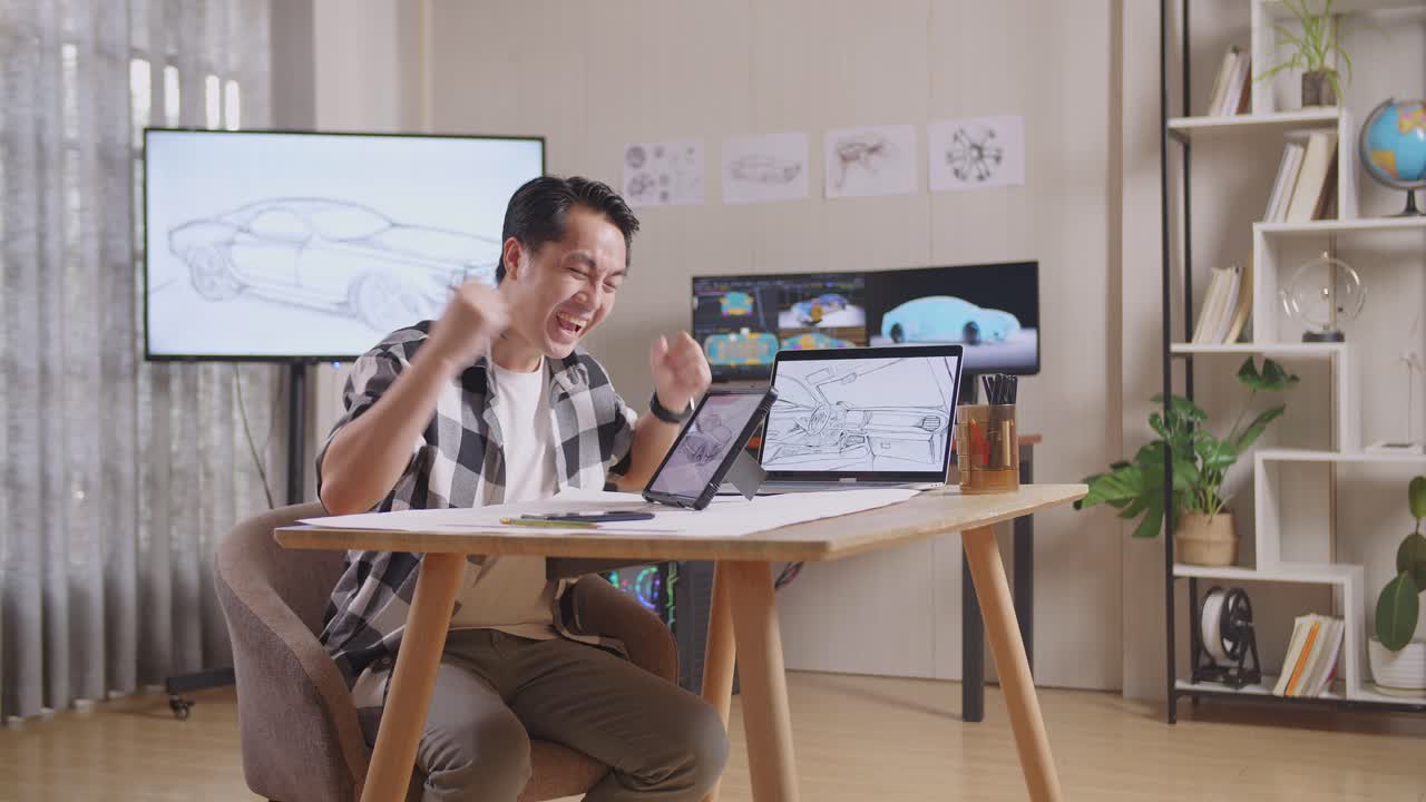 vista lateral de un hombre asiático celebrando el éxito dibujando un nuevo concepto de diseño de automóvil en una tableta en el estudio con televisión y computadoras muestra un modelo de automóvil eléctrico en 3d