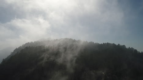 천천히 움직이는 드론은 산 꼭대기에 굴러가는 안개를 습니다.