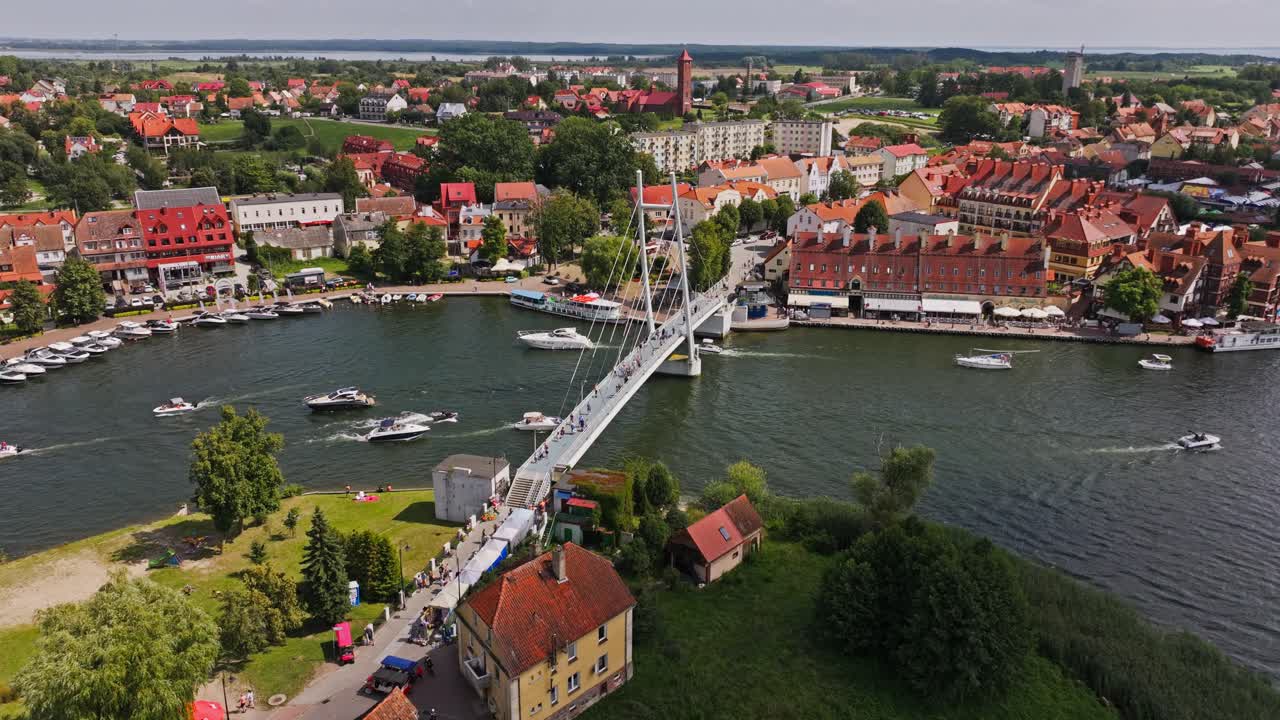 Ripresa aerea estiva a Mikołajki, Polonia, con turisti e barche intorno al ponte pedonale.