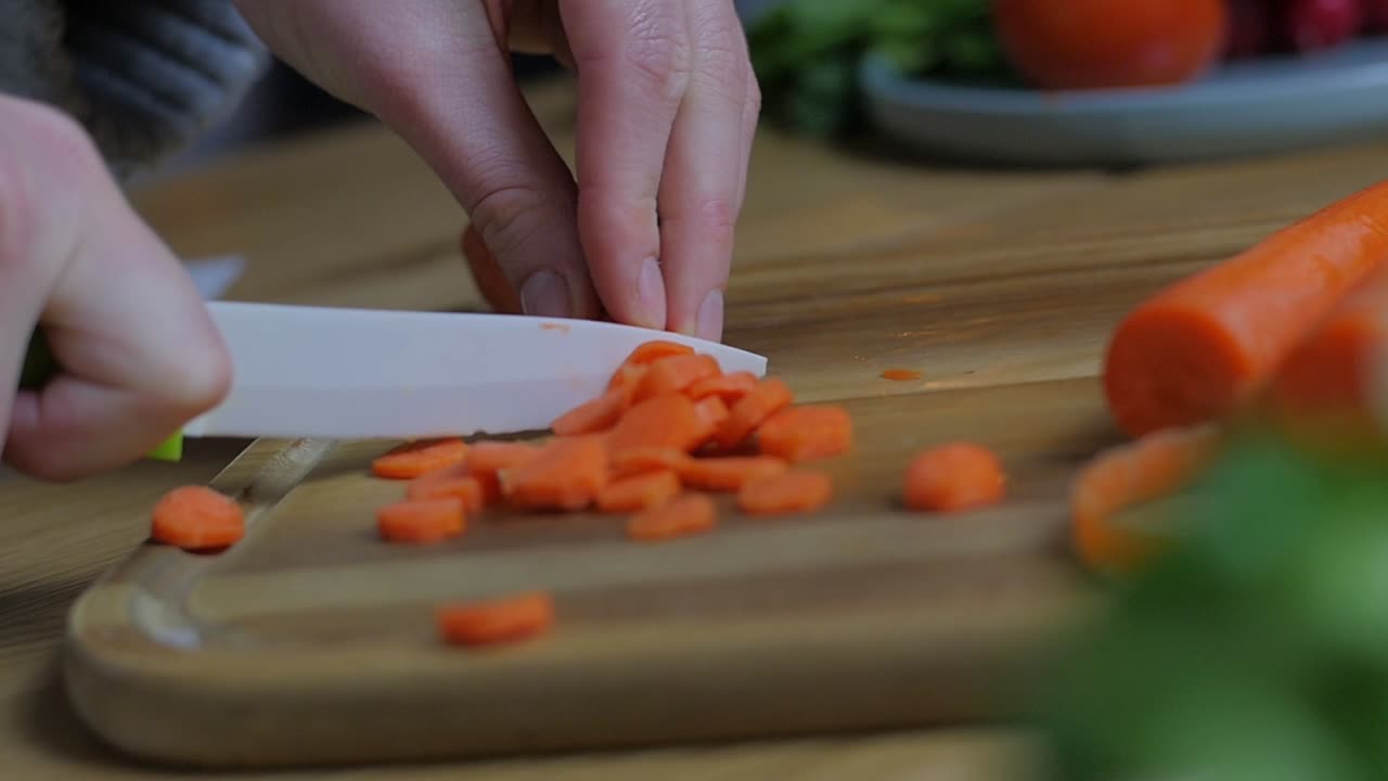Cutting carrots on a table next to salad. 60 FPS