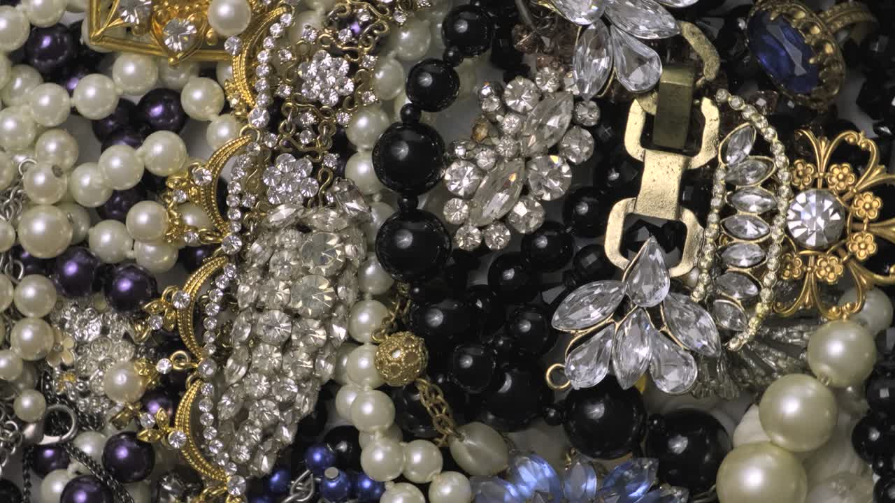 conjunto de joyas, fondo de rotación de oro amarillo y blanco. muchas hermosas joyas de moda femeninas con piedras preciosas brillantes, perlas y diamantes para mujeres. riqueza y concepto de lujo, primer plano, macro