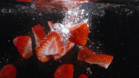 fresh cut red strawberries drop in water with bubbles in slow motion delightful