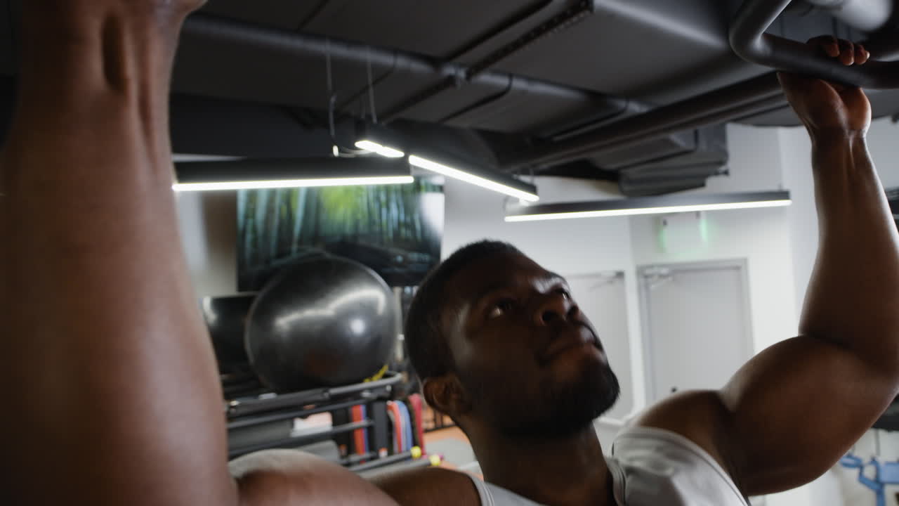 hombre realizando pull-ups en un gimnasio