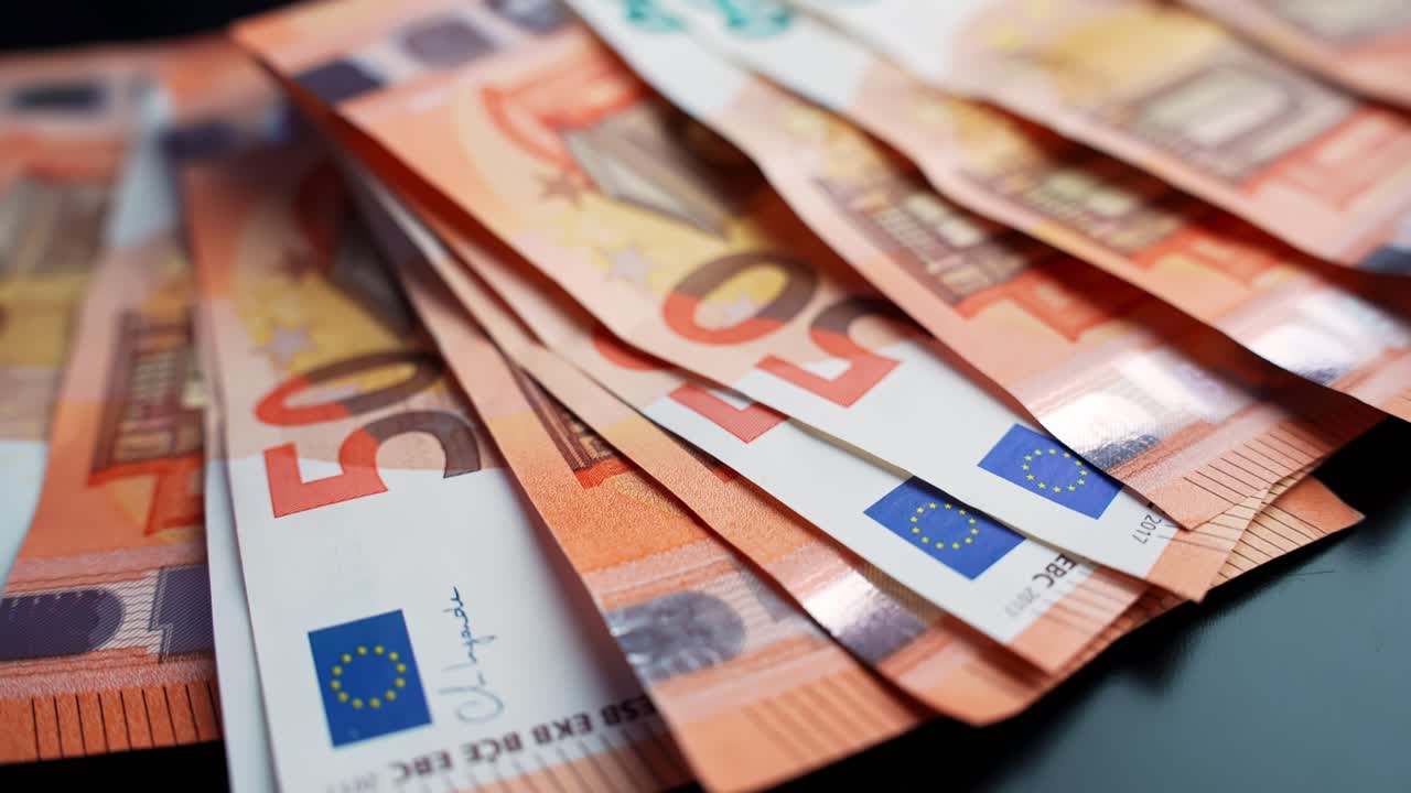 Toma macro de billetes de 50 € extendidos sobre un fondo oscuro con espacio para texto y poca profundidad de campo. Concepto para pagos, ahorros, presupuestos y finanzas personales