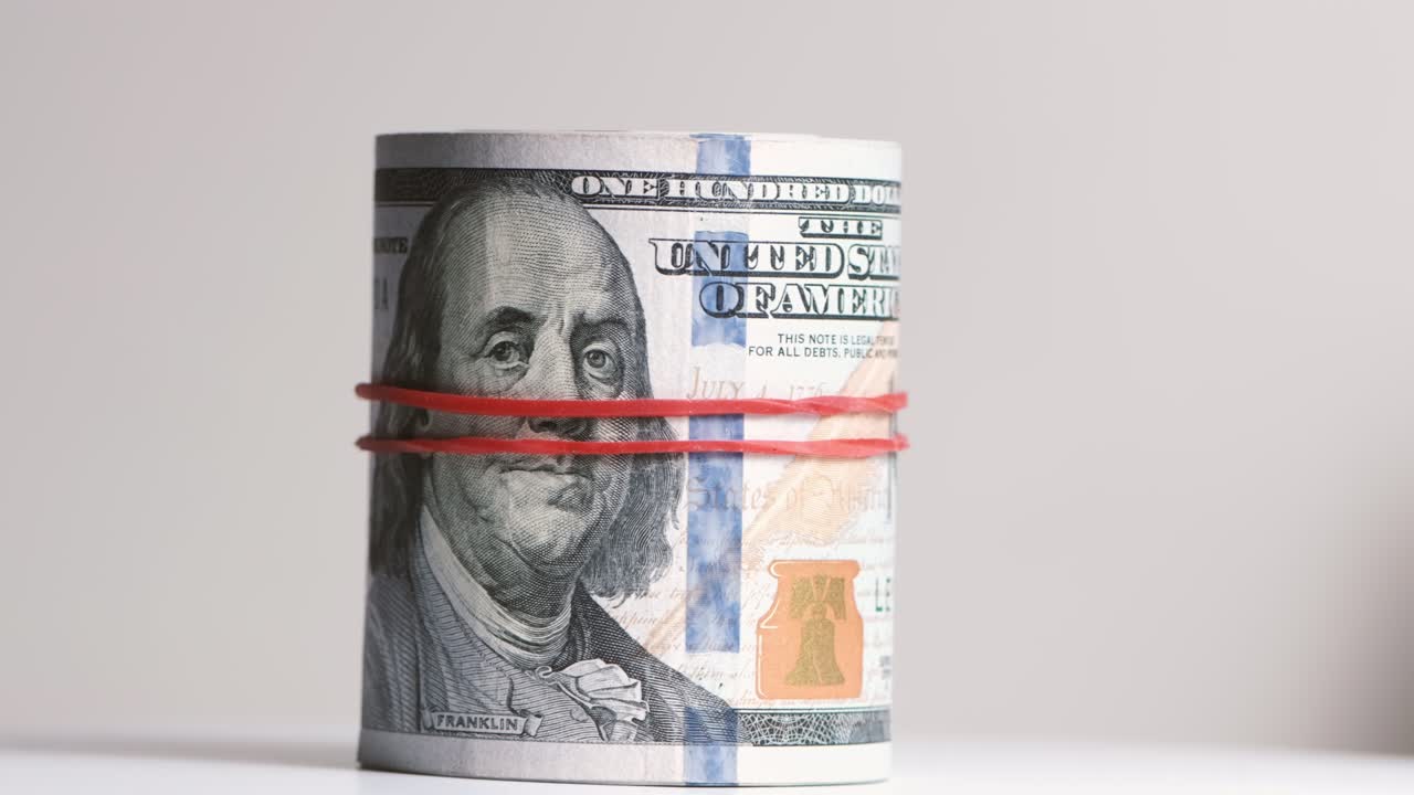 el rollo de billetes de cien dólares está estirado con una banda elástica.