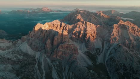 Aerial-drone-view-from-left-to-right-of-the-iconic-Punta-Sud-di-Fanes,-Punta-Nord-and-Monte-Ciaval-peaks-in-the-Dolomites-of-Cortina-D'Ampezzo,-Italy-at-sunrise