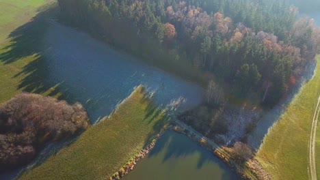 aerial descend over forest and lake in the morning sun