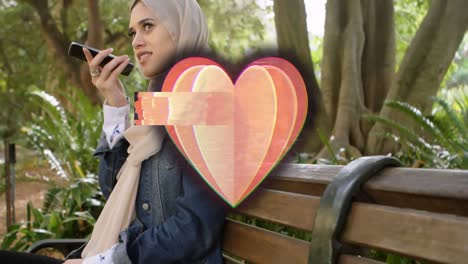 animation of heart icon over muslim woman using smartphone