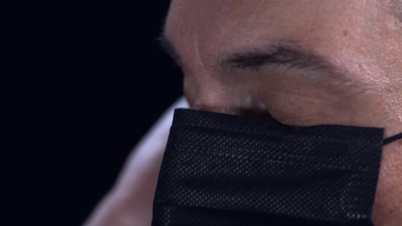 un hombre adulto se pone una máscara negra durante la pandemia de covid-19