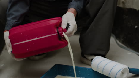 worker pouring paint into tray