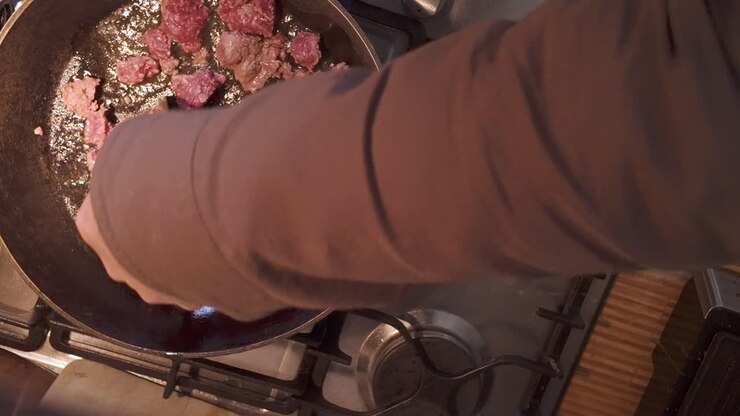 Cook using spatula, stirring Mince beef frying in hot oil on gas hob TOP DOWN
