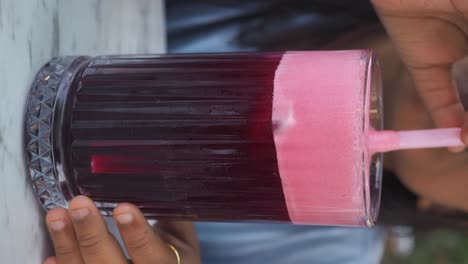 close-up of a refreshing red drink with pink foam and hands