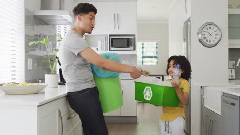 happy biracial man and his son sorting waste in kitchen