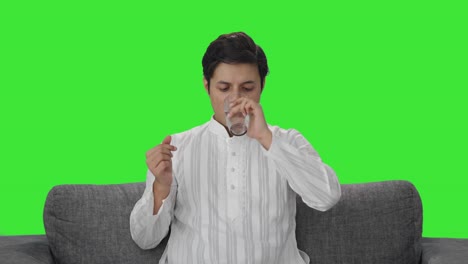 sick indian man taking medicine green screen