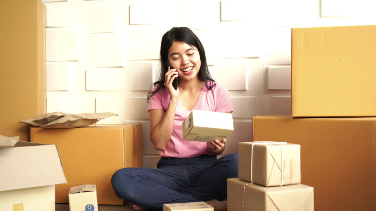 propietaria de una empresa asiática que trabaja en casa con una caja de embalaje en el lugar de trabajo
