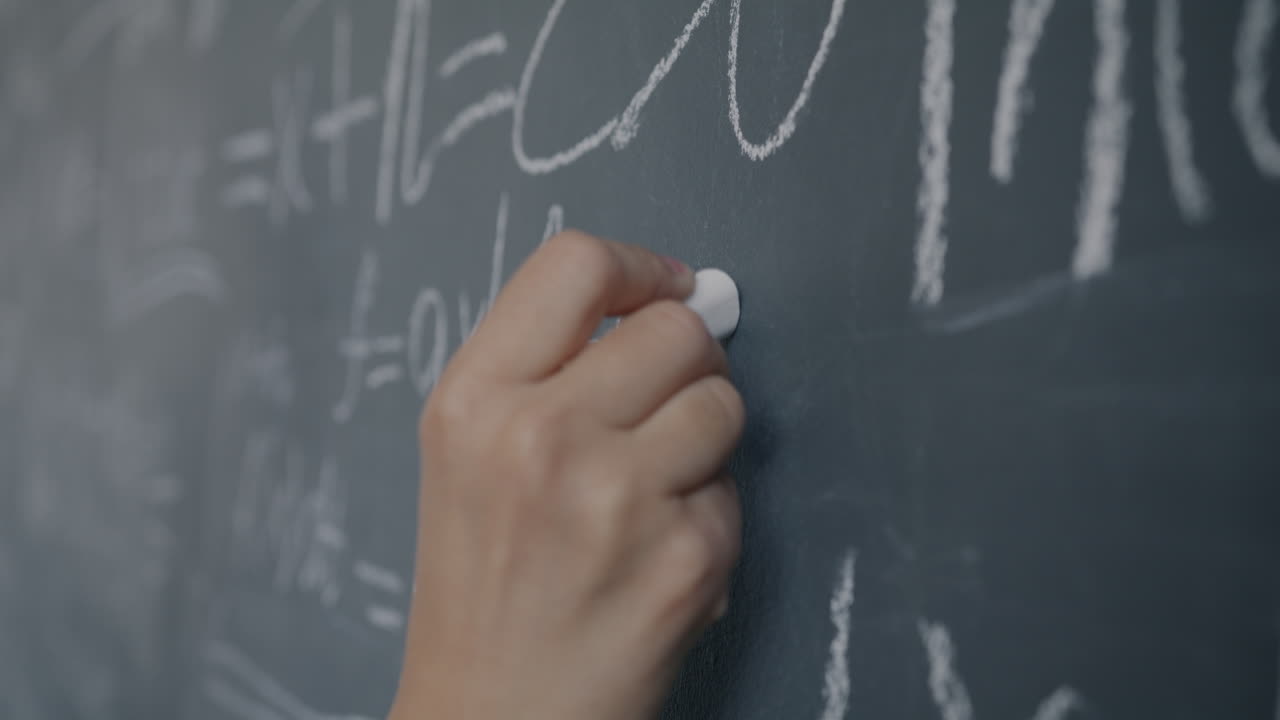Person Writing Equations on a Chalkboard