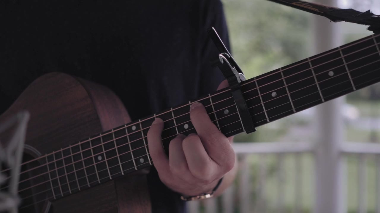 Uomo che suona la chitarra e canta sotto un gazebo sotto la pioggia - Primo piano sulla chitarra