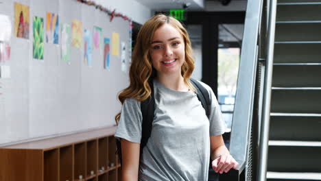 portrait of female high school student standing by stairs in college building