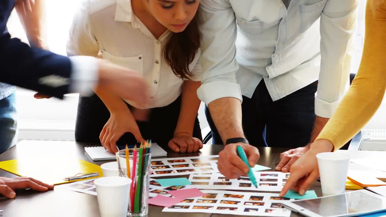 그래픽 디자이너 들 이 사진 을 보고 토론 하고 있다