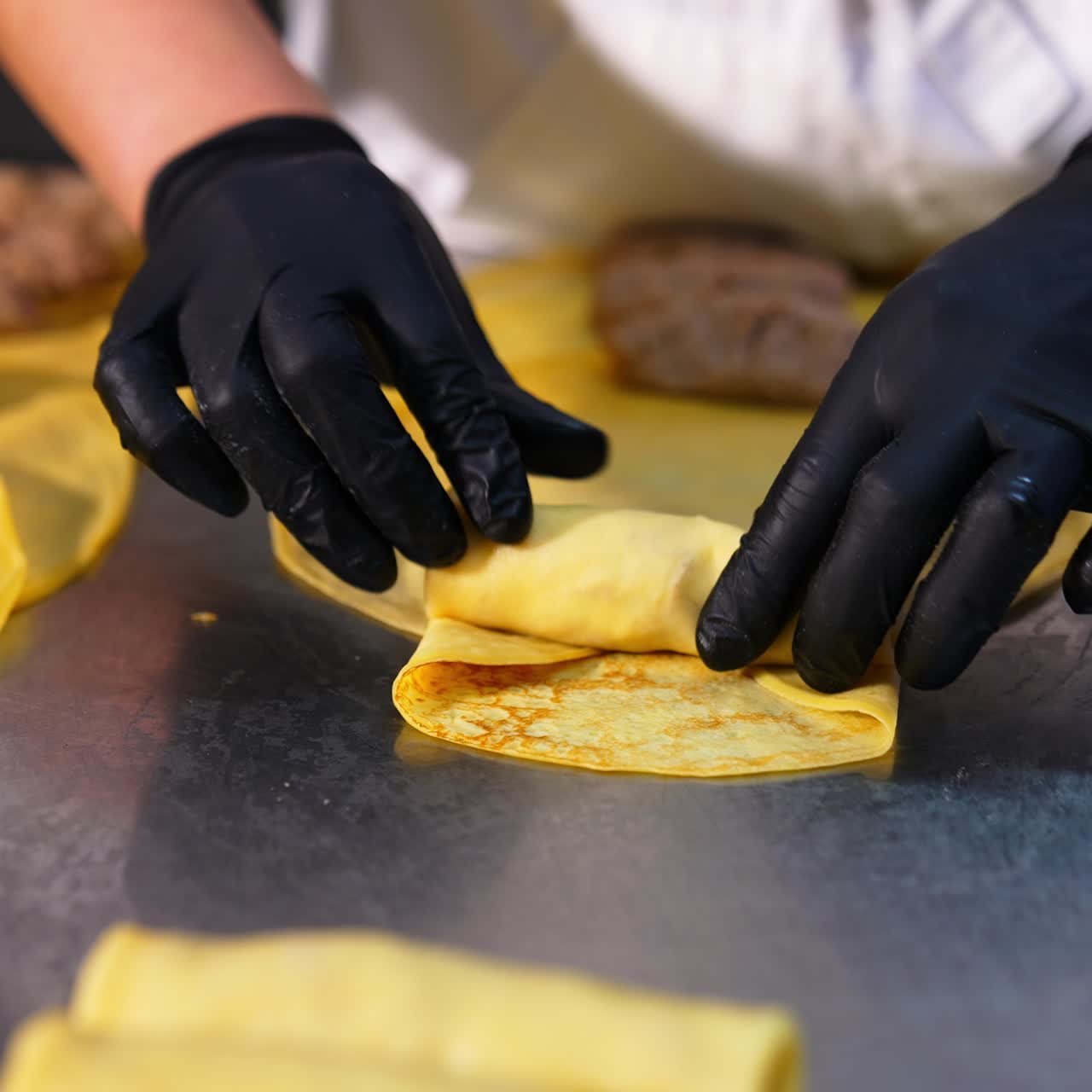 Fried meat stuffing is put and rolled into yellow thin pancake. Chef makes stuffed crepes handmade. Close up