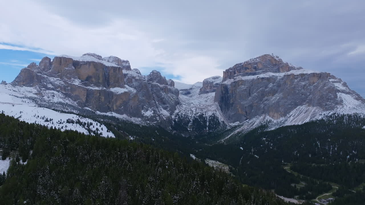 imágenes aéreas en un día nublado volando lejos de una cadena montañosa gigante e imponente en los dolomitas.
