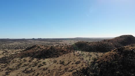 colinas cubiertas de hierba, arena roja, arbustos, árboles y rocas son capturadas por una cámara que se mueve sobre una gran sabana africana