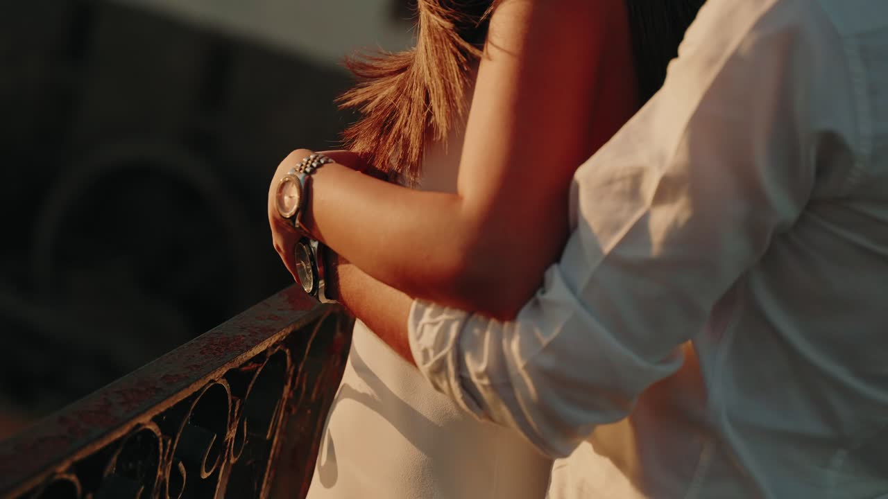 Intreccio delicato di arti con lo sguardo rivolto al ferro battuto nel bagliore caldo del tramonto