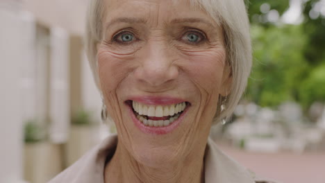 close up portrait of elegant elderly woman laughing cheerful looking at camera enjoying retirement urban city background