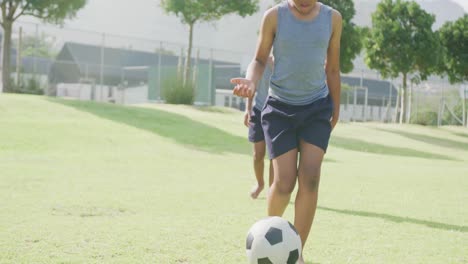 video of two african american schoolboys playing football barefoot in field