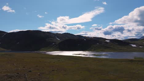 aerial view of a serene landscape featuring lush greenery, tranquil lakes and majestic mountains under a partly cloudy sky