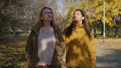 caucasian women walking together in park in autumn