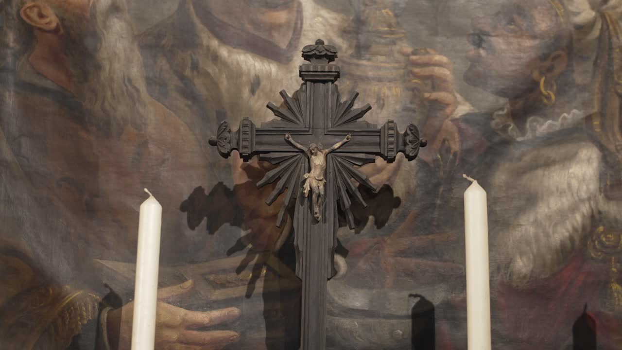 Dark crucifix and candles placed in front of a painted religious scene in Portugal