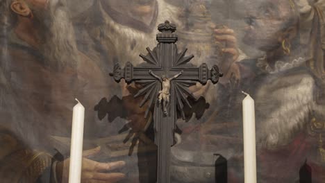 dark crucifix and candles placed in front of a painted religious scene in portugal