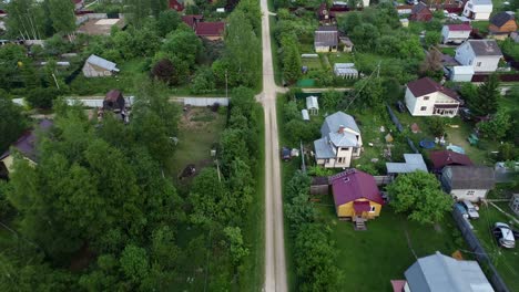 the village road. the car rides along the road between trees and houses.