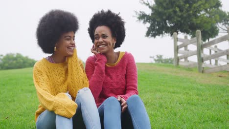 two mixed race women laughing in park