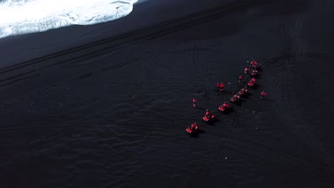 aerial view of red quad bikes on iceland black sand beach, next to the ocean