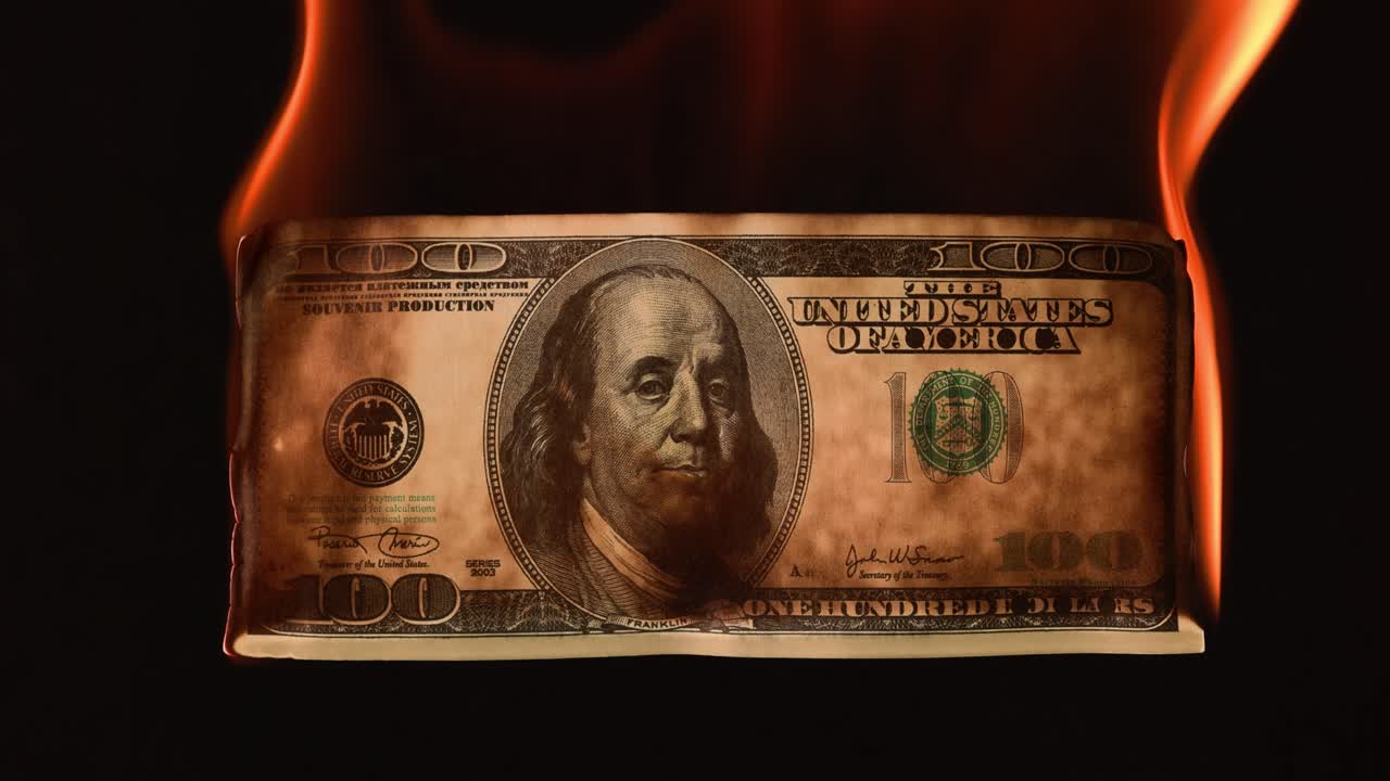 USA dollar bill money is burning in the fire, the concept of the economic crisis of inflation and currency devaluation.