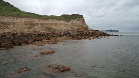 low-Low-angle-aerial-shot-at-Cayton-bay-with-Scarborough,-North-Yorkshire-cloudy