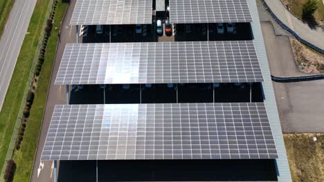 aerial view of solar panels installed as shade roof over parking lot with parked cars for effective generation of clean electricity. photovoltaic technology integrated in urban infrastructure