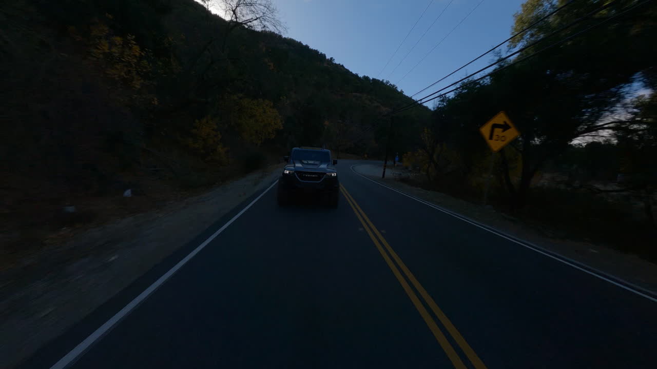 도로에서 빠르게 운전하는 검은색 픽업 트럭의 fpv 드론 샷