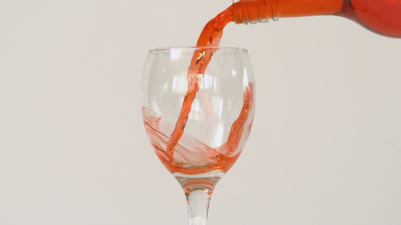 Super-Zeitlupe von orangefarbener Flüssigkeit, die in ein Glas gefüllt wird