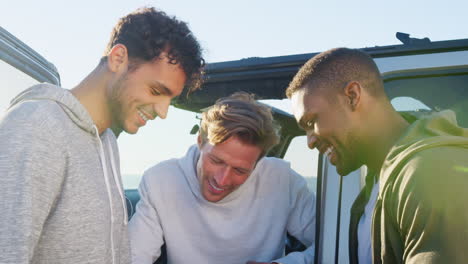 three young men on a road trip hanging out by their car