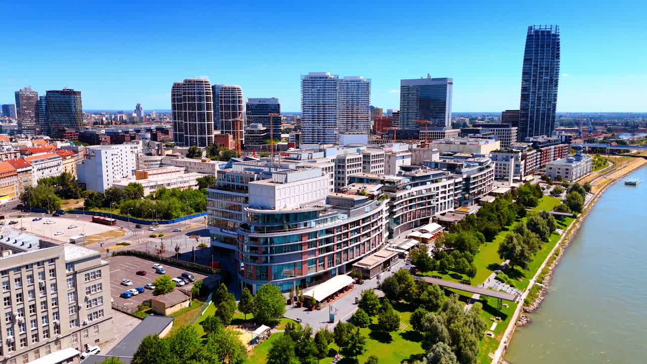 Flying above the beautiful green park on the waterfront of the Danube River. Aerial perspective on the sunny cityscape of Bratislava, Slovakia.