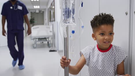 african american male doctor walking with child patient at hospital